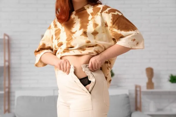 Image of woman trying to do her trousers up after pregnancy weight gain Craigentinny