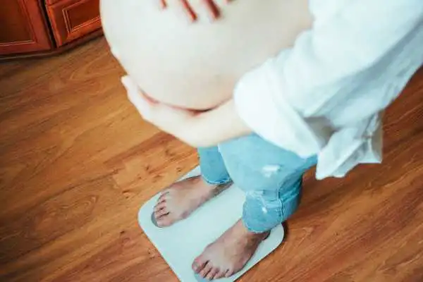 Image of woman weighing herself and experiencing weight gain through pregnancy Craigentinny